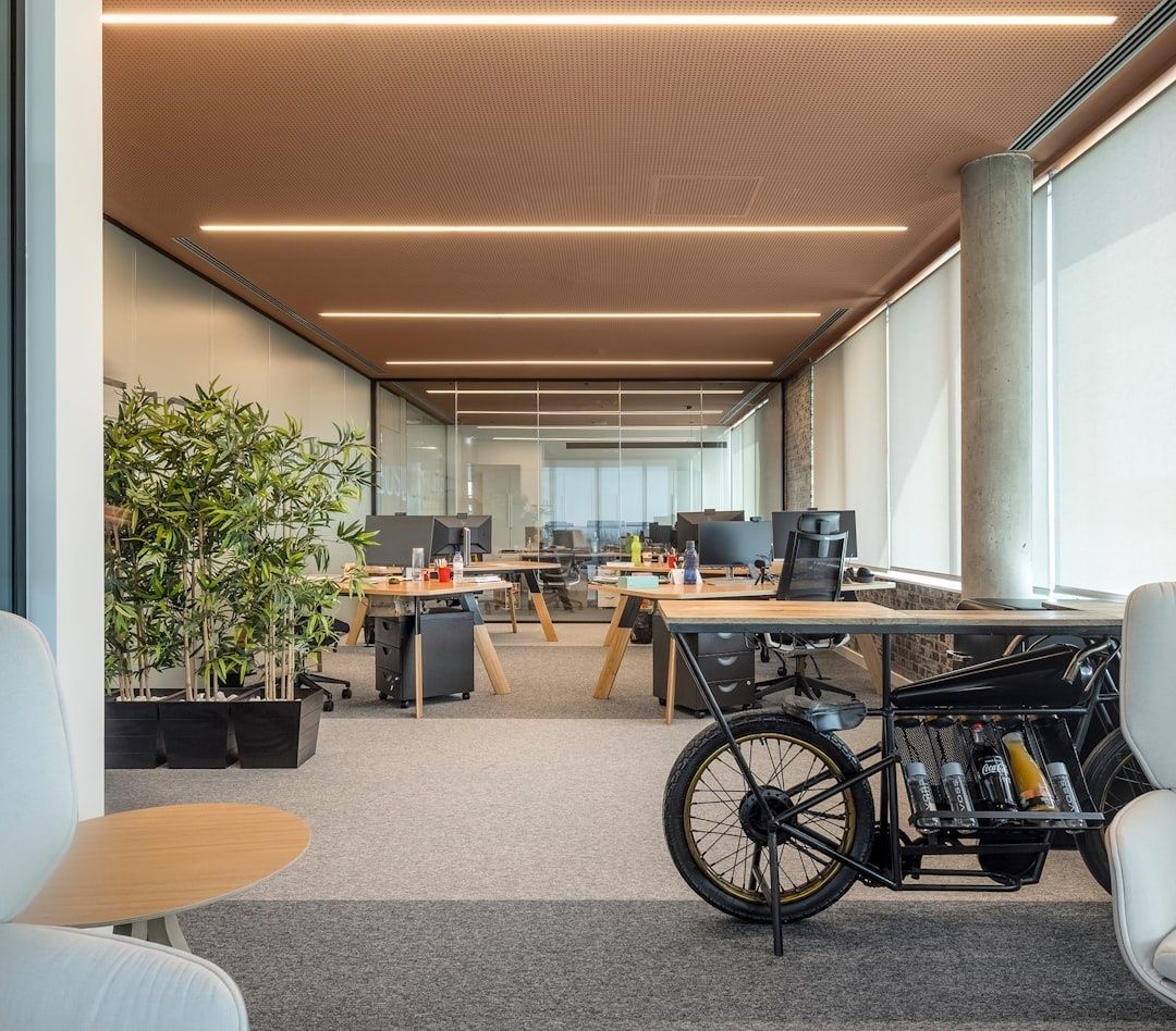 Moderne kontor med arbejdspladser, planter og ladcykel ved vinduer